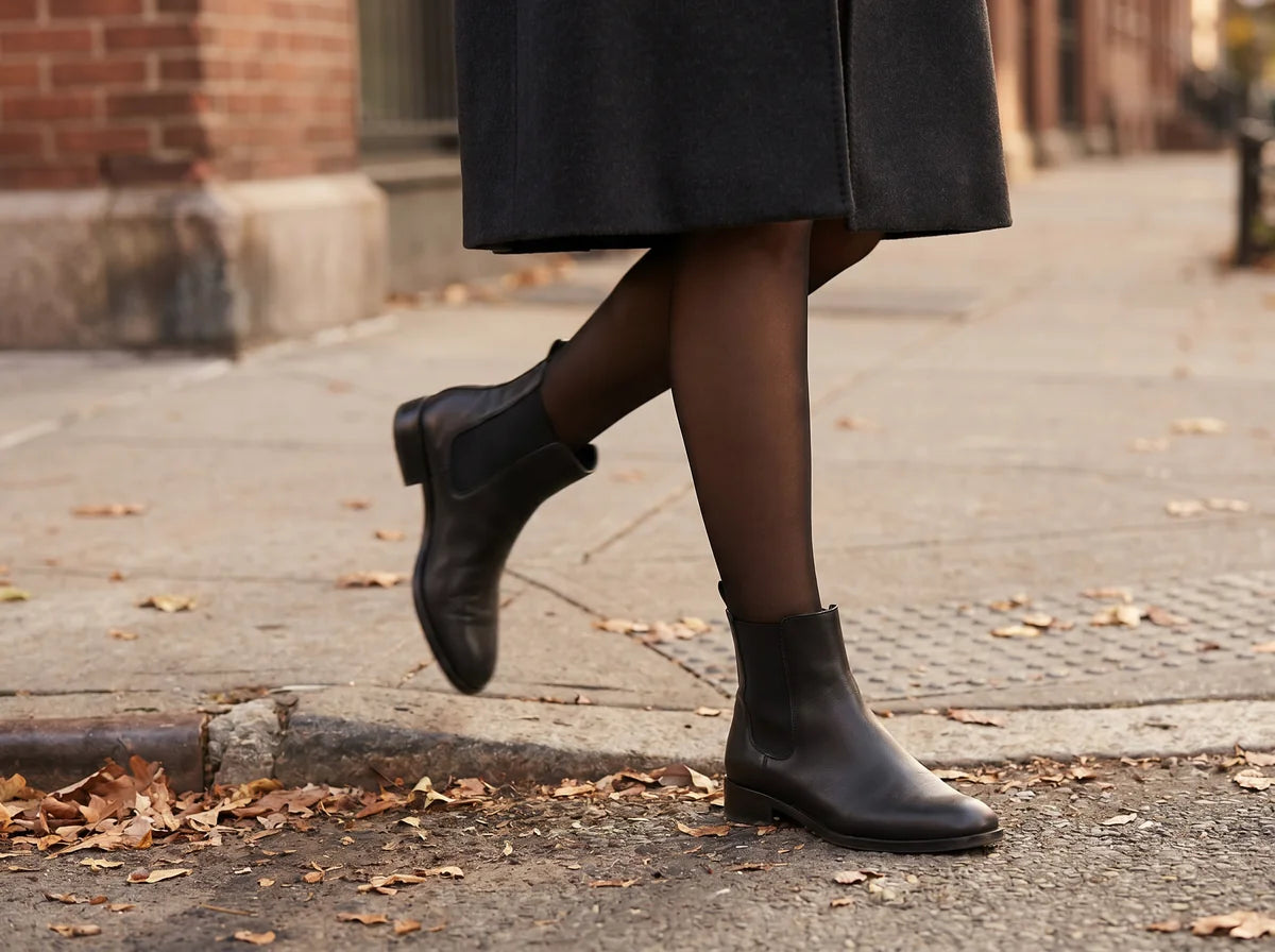 A woman in sheer black Tightknit tights mid-stride on a winter city sidewalk